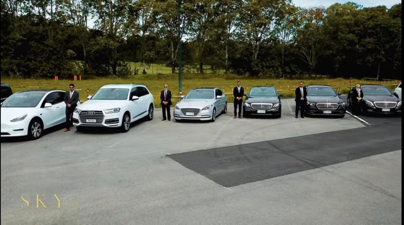 The Sky Transfers fleet lined up with a chauffeur standing beside each vehicle.
